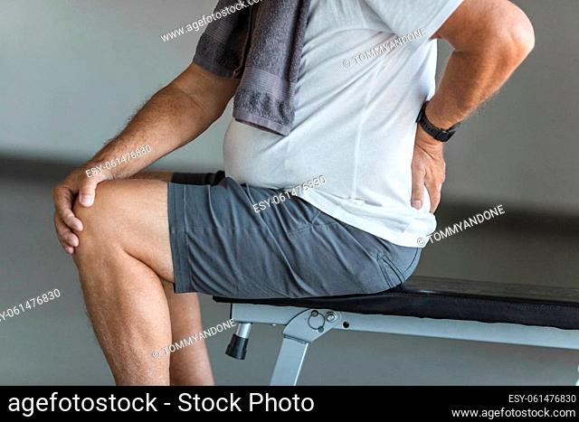 Active senior man in gym with back pain
