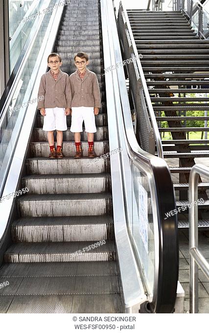 Twin brothers standing on escalator