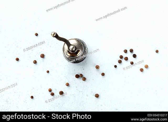 Allspice, Jamaica pepper. Black peppercorns with a vintage pepper mill, overhead shot with copy space