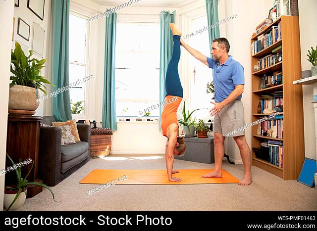 Fitness instructor guiding mature woman to do exercise at home