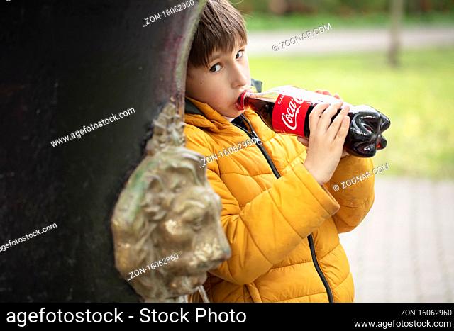 Belarus, city of Gomel, 08 May 2020. City Park. The child drinks Coca Cola from a glass bottle