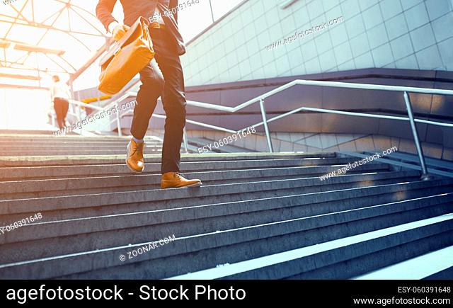 Businessman in suit walking down on concrete steps. Stylish business worker wearing formal clothes making his way down steps