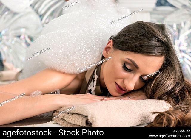Beautiful young woman enjoying foam treatment during traditional Turkish bath at luxury spa and wellness center