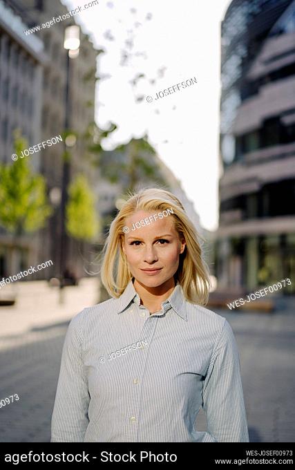 Confident beautiful blond businesswoman standing in city