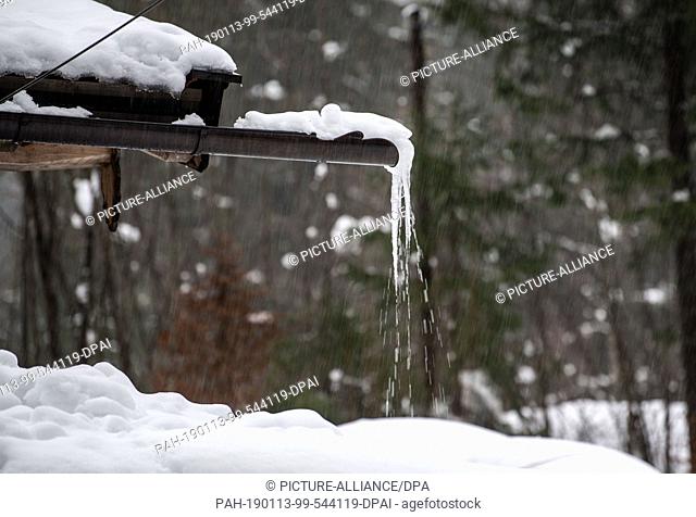 13 January 2019, Bavaria, Rottach-Egern: Drops fall from an icicle on a rain gutter to the ground. After the heavy snowfalls of the past few days
