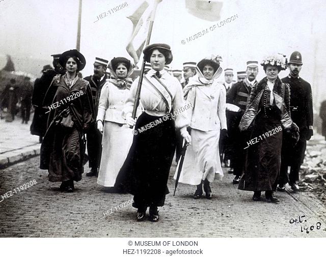 Daisy Dugdale leading a procession, London, 1908. Wearing the suffragette uniform in the colours of purple, green and white, Daisy Dugdale leads a brass band