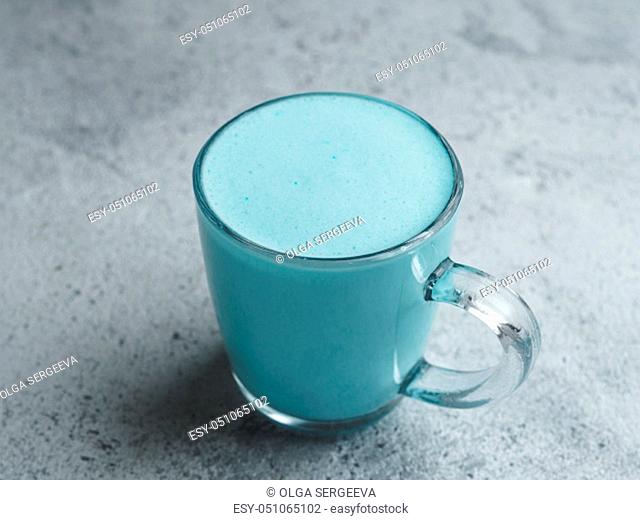 Trendy drink: Blue latte. Top view of hot butterfly pea latte or blue spirulina latte on gray cement textured background. Copy space for text