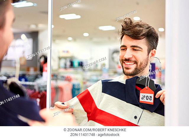 Junger Mann beim Shopping probiert ein Hemd im Einzelhandel Discount