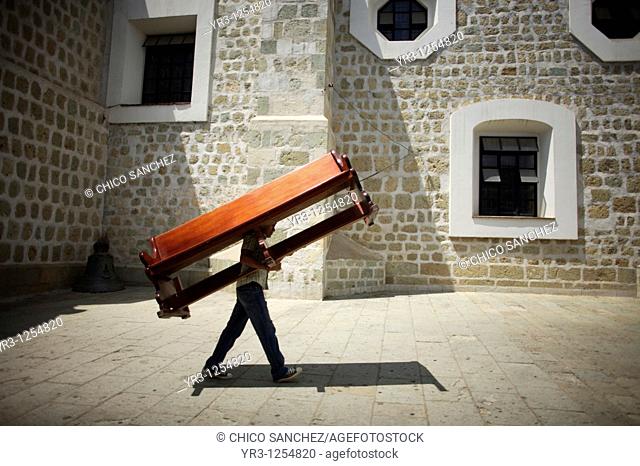 A man carries a church bench to the Basilica de la Soledad, or Solitude Basilica, after a holy week procession in Oaxaca, Mexico