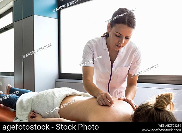 Close up acupuncturist applying acupuncture needles to womanƒ.s back