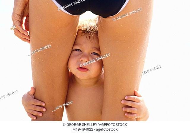 child looking between his mothers legs