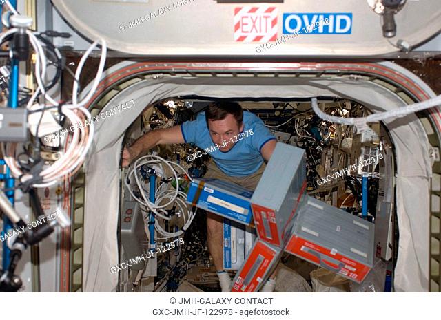 Cosmonaut Yury Lonchakov, Expedition 18 flight engineer, moves storage containers through a hatch on the International Space Station