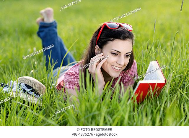 woman lying with book in meadow - , 05/04/2014