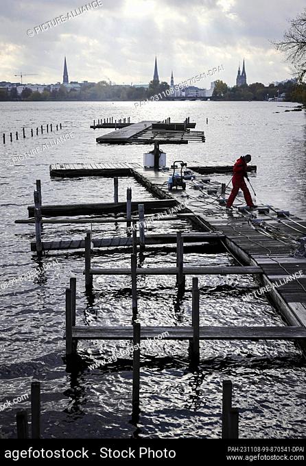 08 November 2023, Hamburg: A high-pressure cleaner is used to clean the jetty and moorings of Bodo's Bootssteg at the Rabenstraße jetty on the Outer Alster and...