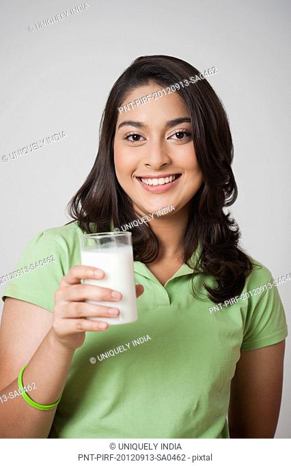 Teenage girl holding a glass of milk and smiling