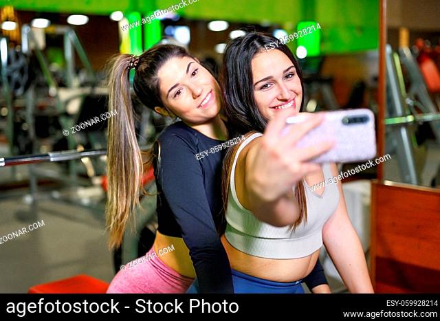 Portrait of two smiling sporty women taking a selfie photo in the gym. High quality photo