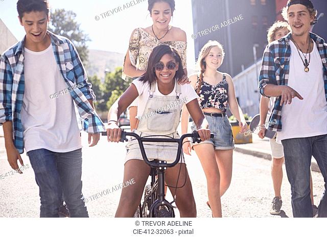 Teenage friends with BMX bicycle on sunny urban street