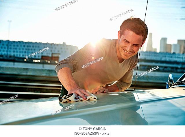 Man polishing car smiling, Los Angeles, California, USA