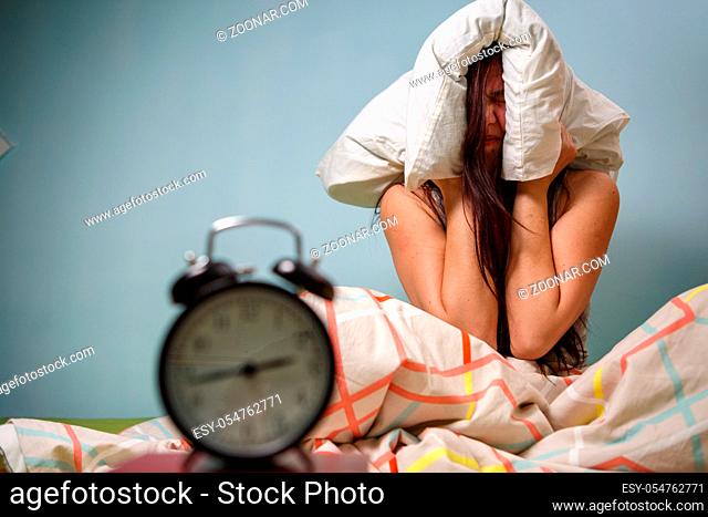 Woman with a pillow over her head, has trouble sleeping. Insomnia concept