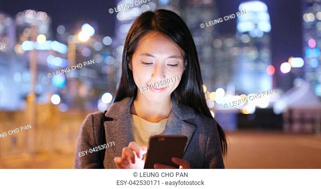 Businesswoman use of mobile phone in city at night
