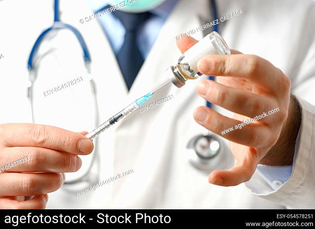 The doctor prepares the syringe for vaccination