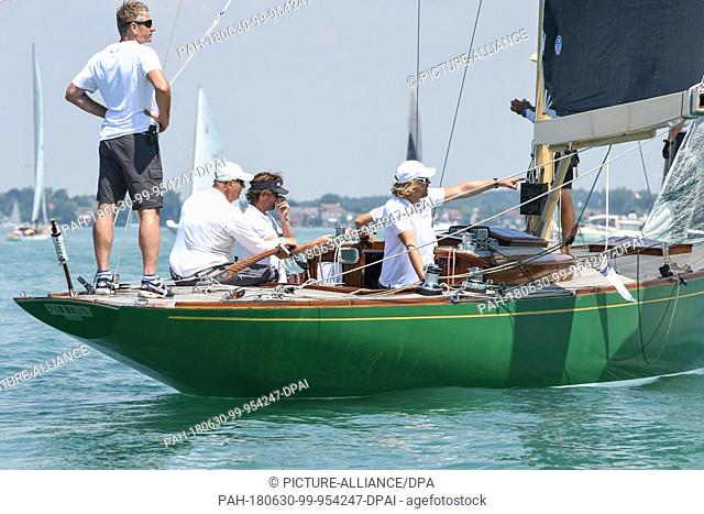 30 June 2018, Germany, Langenargen: King Harald V. of Norway (2-L) sitting at the tiller of his yacht ""Sira"" during the Aguti Classic Cup