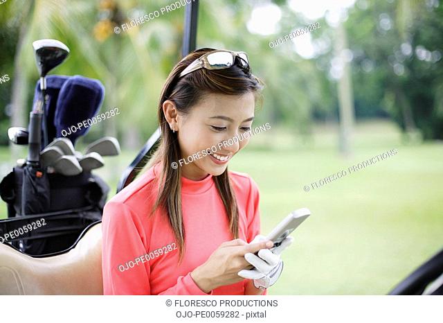 Woman in a golf cart looking at her mobile phone