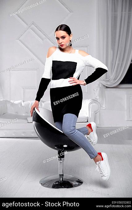 Lovely woman dressed in a sweater and jeans posing in the studio