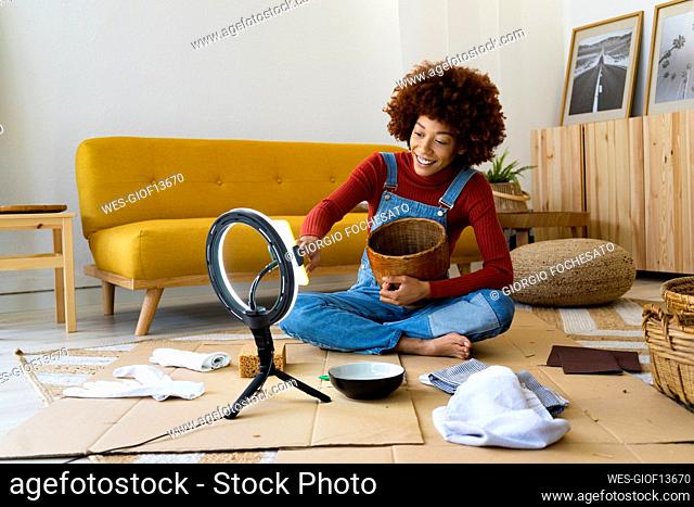 Redhead woman adjusting mobile phone on ring light in living room