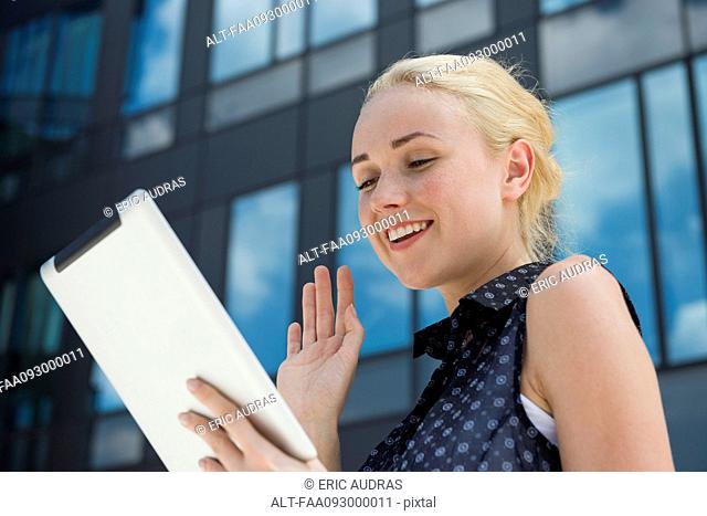 Young woman waving at digital tablet