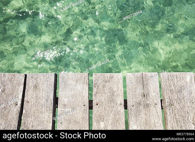 Wooden pier over shallow clear turquoise blue water