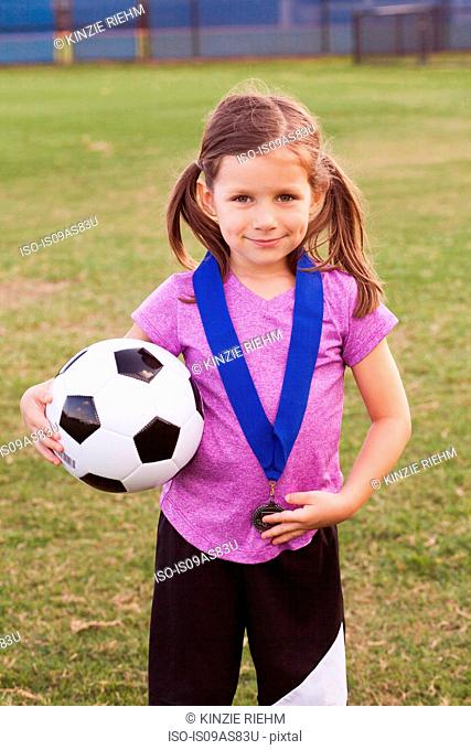 Portrait of girl football player with medal on practice pitch