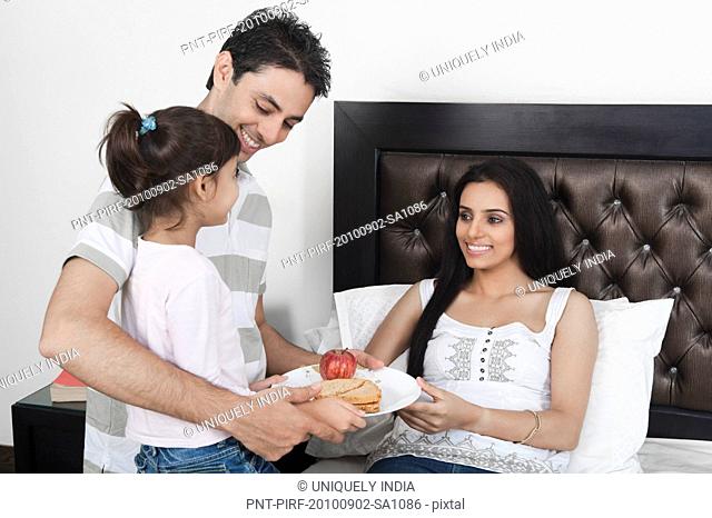 Girl with her father giving breakfast to her mother