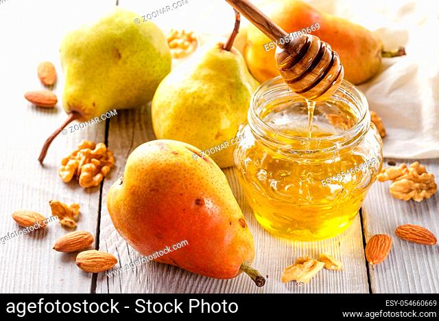 Tasty pears with honey and nuts on wooden table