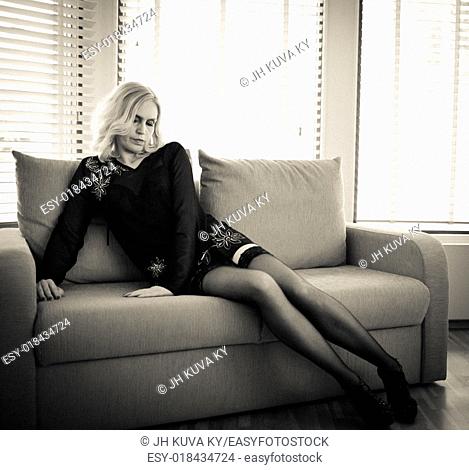 Mature woman in sexy stockings sitting on sofa