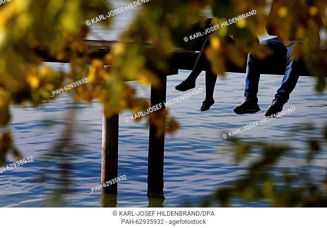 Excursionists dangle their legs off a dock on Lake Ammer near Stegen, Germany, 24 October 2015. Photo: KARL-JOSEF HILDENBRAND/dpa | usage worldwide