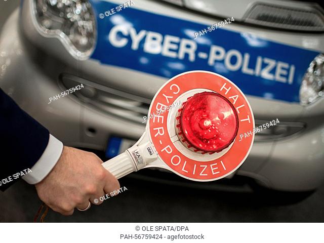 ILLUSTRATION - A man holds a police signaling disc reading 'Halt Cyber-Polizei' (lit. 'Stop - cyber police') in front of a 'Smart' car inscribed 'Cyber-Polizei'...