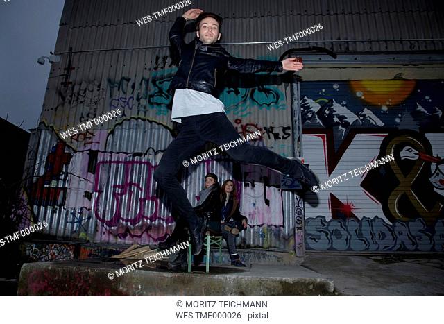 Dancer jumping in front of graffiti
