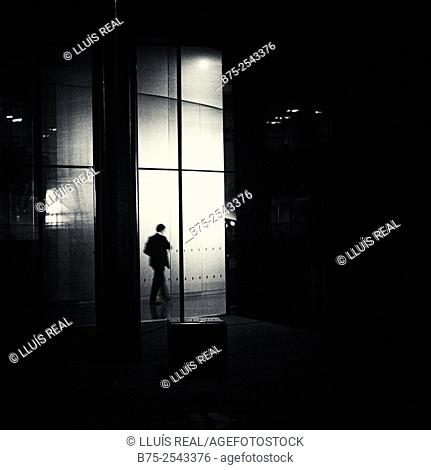Backlit silhouette of an executive unrecognizable men walking in an office corridor. City of London, England, UK, Europe