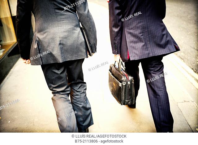 Rear view of two executive walking down the street with a briefcase in hand the City of London, England, UK, Europe