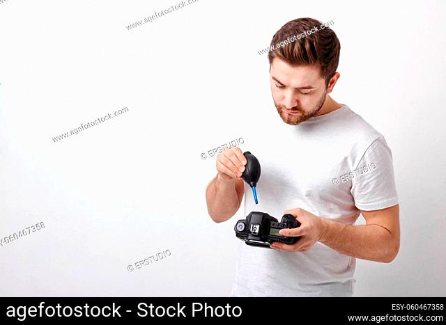 young photographer cleaning camera with vacuum pump. hand blower dust cleaner for camera and lenses