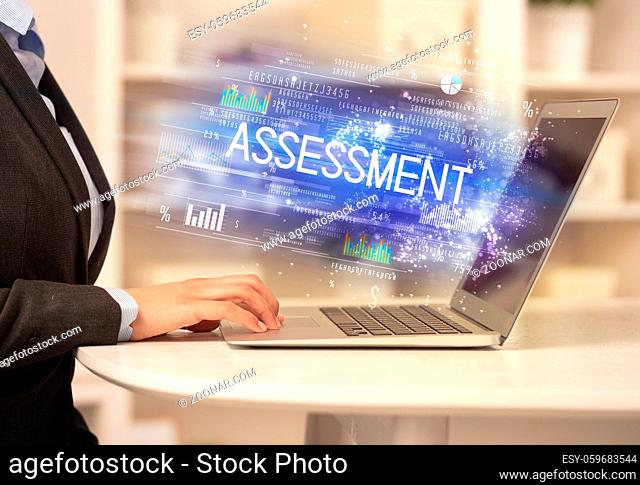 Closeup of businessman hands working on laptop with ASSESSMENT inscription, succesfull business concept