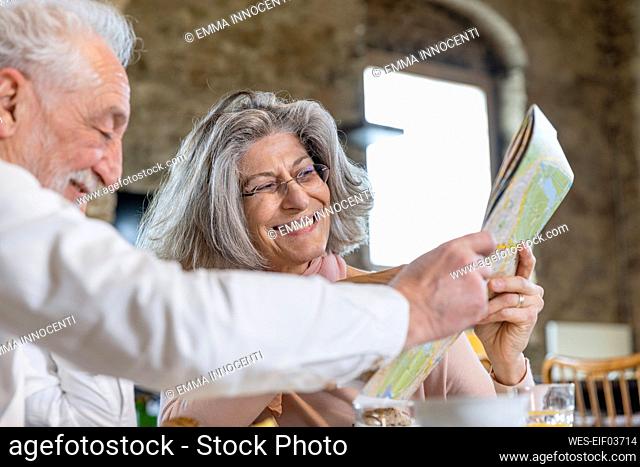 Happy senior couple sharing city map at boutique hotel