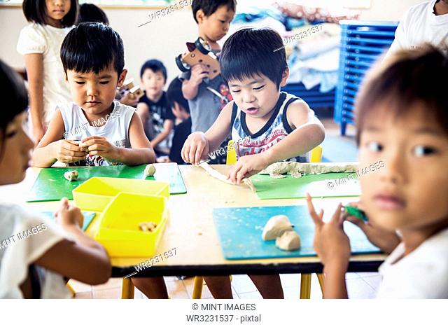 Group of children sitting at table in a Japanese preschool, doing crafts