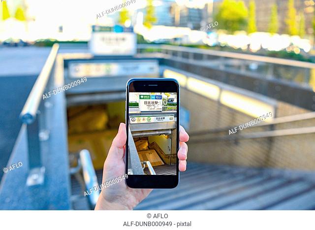 Japanese woman using augumented reality app on smartphone downtown Tokyo, Japan