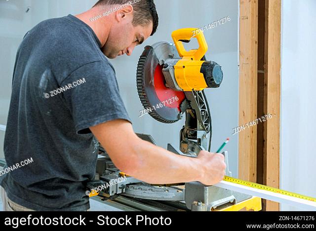 Carpenter cutting wooden trim board on with circular saw. Woodworker works on remodeling home