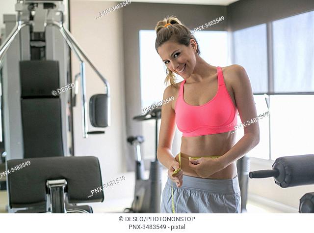 Woman in fitness center measuring her waist