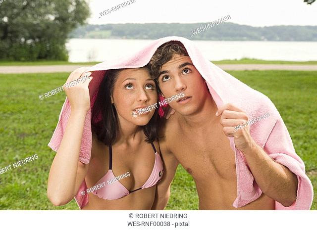 Germany, Bavaria, Starnberger See, Young couple holding towel over heads, portrait, close-up