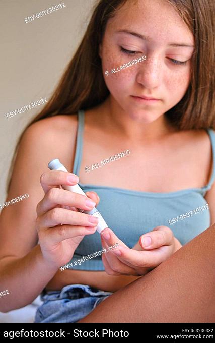 Diabetes and glycemia, a teenage girl examines her sugar level. A blood test for glucose levels, puncturing a child's finger with a lancet