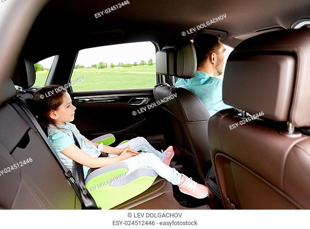family, transport, road trip and people concept - happy little girl in safety seat driving in car with her dad